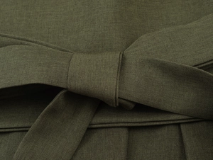 Gros plan sur une ceinture en tissu vert armée nouée en nœud avec coutures précises
