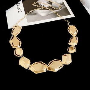 Détail des maillons géométriques facettés du collier doré avec une finition polie