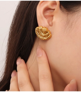 Detail of gold geometric earrings with hammered texture and layered fan-shaped design