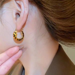 Model wearing 14k gold plated leopard print hoop earrings with realistic texture