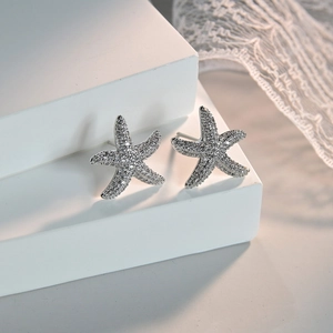 Starfish stud earrings featuring shimmering AAA cubic zirconia on a white geometric stand