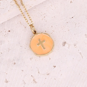 Detail of gold cross pendant with orange enamel on a textured stone background