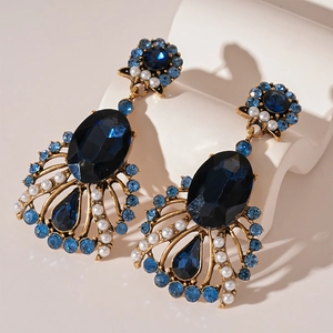 Macro shot of vintage style earrings with blue crystals and pearls in gold finish