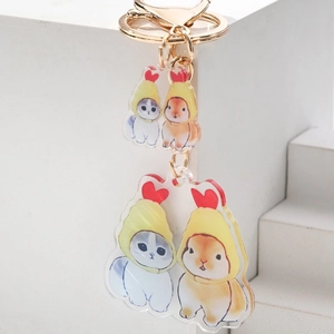 Detailed view of acrylic cat and rabbit keychains with gold chains on white background