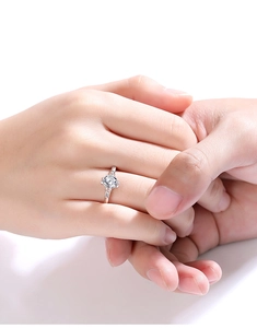 Classic one carat moissanite ring shown on finger in a romantic proposal setting