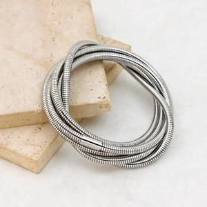Detailed view of silver multi-layer snake bone chain bracelet on textured stone