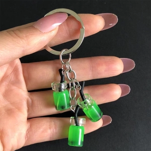 Close-up of a hand holding a green bubble tea keychain with mini resin beverage cups