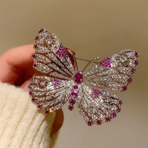Elegant silver butterfly brooch with sparkling crystals and red gems held in hand