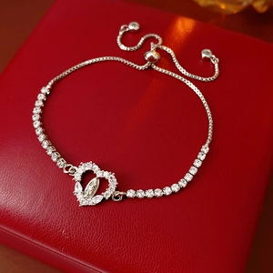 Macro shot of a silver heart Virgin Mary bracelet with zircon inlay on red leather