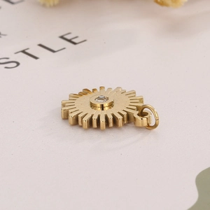 Detail of golden stainless steel sunburst pendant with a clear zircon center inlay