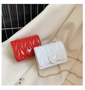 Detail of red and white silicone heart crossbody bags with gold chain and pleated texture