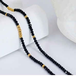 Macro shot of faceted black beads and gold metallic spacers in a beaded necklace