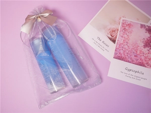 Detail of blue cosmetic bottles in purple organza drawstring bag with pearl and bow