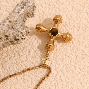 Detailed view of 18K gold ship helm pendant with brown gemstone on a twist chain necklace