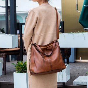 Rear view of a model wearing a vintage caramel brown PU leather tote bag in soft natural light