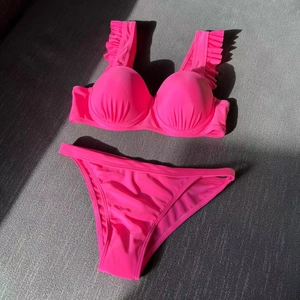 Hot pink two-piece bikini featuring ruffled straps, ruched cups, and side cutout bottoms