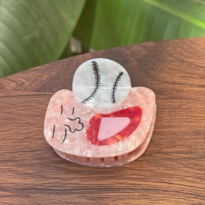 Détail de la pince à cheveux en acétate rose avec motifs baseball et lèvres rouges