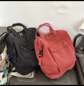 Detail of vintage washed canvas backpacks in black and brick red with buckle closures