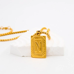 Gold stainless steel necklace with rectangular letter N pendant on white stone base