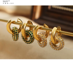 Dettaglio di orecchini a cerchio placcati oro 18K con gemme verdi e bianche pavé