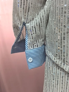 Close-up of silver sequin blazer fabric with striped cotton cuffs and white button details