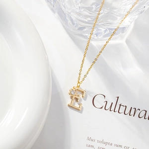 Detailed view of a gold letter E pendant necklace with a sparkling zircon stone inlay