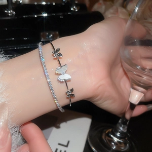 Detailed close-up of a silver butterfly zircon bangle and diamond tennis bracelet set