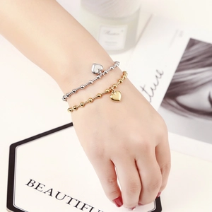 Close-up of gold and silver beaded bracelets featuring heart charms on a model wrist