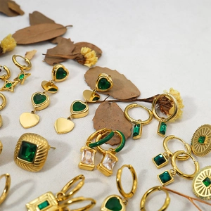 Golden luxury jewelry set featuring green and white zircon earrings on natural background
