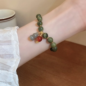 Detail of green bodhi seed beaded bracelet with gourd pendant on model's wrist