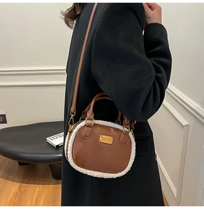 Detail of brown leather handbag featuring white plush faux fur trim and gold hardware