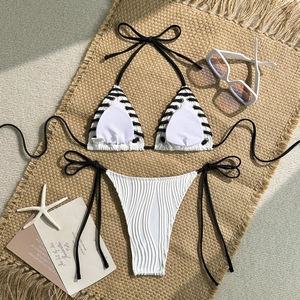 Flat lay of white ribbed triangle bikini set with black side ties on a beach mat
