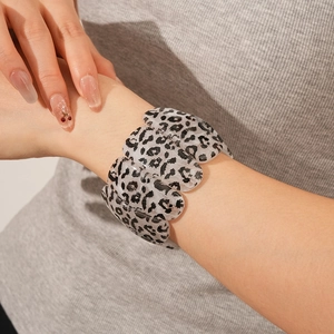 Gros plan d'un large bracelet en acrylique léopard au poignet avec design élastique