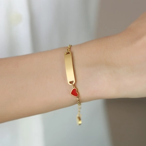 Gold stainless steel bracelet featuring a rectangular bar plate and a red heart pendant