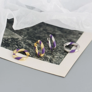 Macro shot of twisted s925 silver hoop earrings with purple enamel spiral stripes