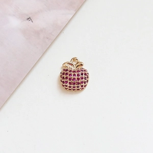 Close-up of a gold-plated apple pendant with red cubic zirconia and metal base