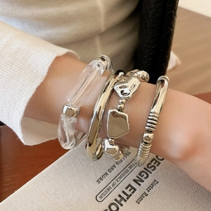 Dettaglio di un set di bracciali geometrici irregolari in metallo argentato da donna