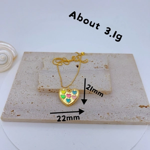 Gold-plated heart pendant with colorful zircon stones on a rustic stone background