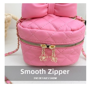 Macro view of smooth double zippers with floral metal charms on a quilted pink bag
