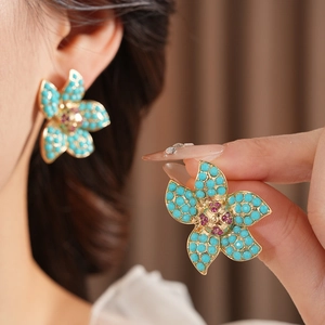 Macro shot of vintage gold flower earrings with turquoise beads and red crystal centers