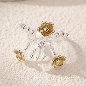 Macro shot of silver ring with three golden flowers and botanical branch details