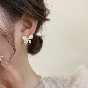 Détail de la boucle d'oreille papillon élégante avec nacre blanche et métal doré sur modèle
