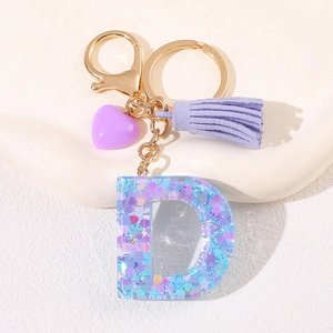 Close-up of purple resin letter D keychain with heart pendant and soft suede tassel