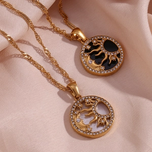 Dettaglio di collane d'oro con ciondoli sole e luna su un tessuto di seta rosa