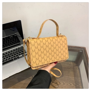 Detail showing vintage tan crossbody bag with M letter print and gold hardware buckle