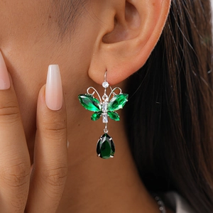 Close-up of green crystal butterfly drop earrings with teardrop gems on model
