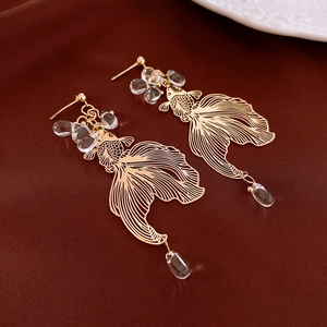 Detailed view of golden goldfish earrings with hollow metalwork and clear crystal beads