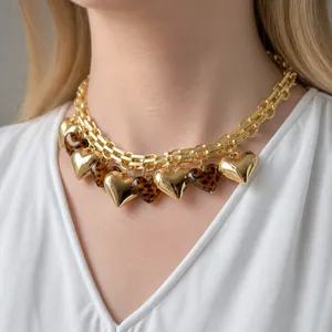 Primo piano di una collana a catena dorata con ciondoli a cuore in metallo e leopardo.