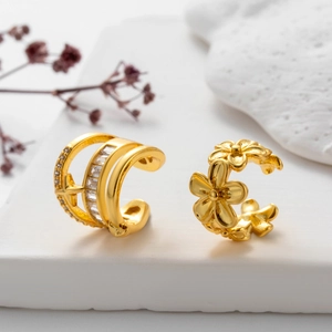 Dettaglio di ear cuff dorati con zirconi micro-pave, stelle e motivi floreali fini