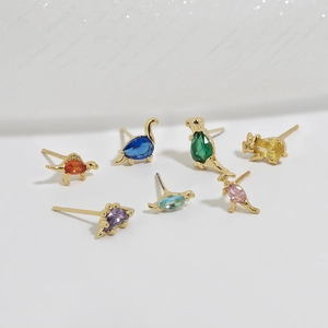 Close-up of golden dinosaur stud earrings with colorful cubic zirconia inlays